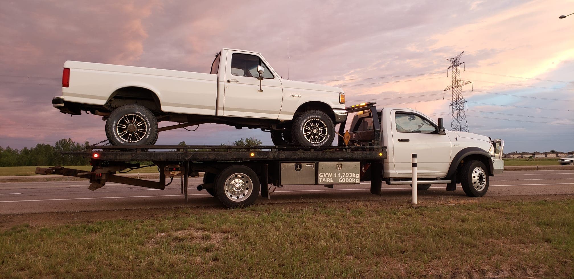 Tow truck carrying a pickup truck at sunset